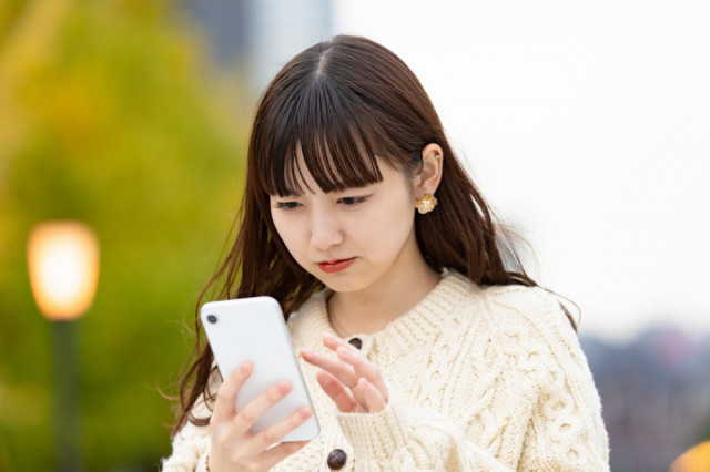 スマホをみる女性の写真